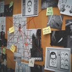 Detective board with stickers, photos, map and clues connected by red string on white brick wall