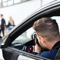 Private Detective Taking Photos Of Man And Woman On Street