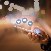 Woman hands using mobile smartphone in the street with icon social media