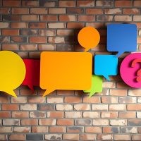 Colorful speech bubbles and question mark on a brick wall background. Colorful speech bubbles and question mark on a brick wall background.