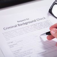 Close-up Of Person Hand Filling Criminal Background Check Application Form Close-up Of Person Hand Filling Criminal Background Check Application Form