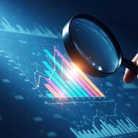 A hand holds a magnifying glass over a digital display of colorful bar and line graphs, emphasizing analysis and data scrutiny in a dark, focused setting.