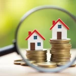 Miniature houses on coins under the magnifying glass, concept finance estate
